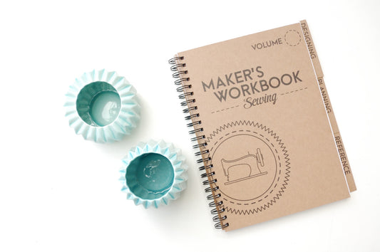 A brown paper bag colored spiral notebook that says Maker's Workbook Sewing