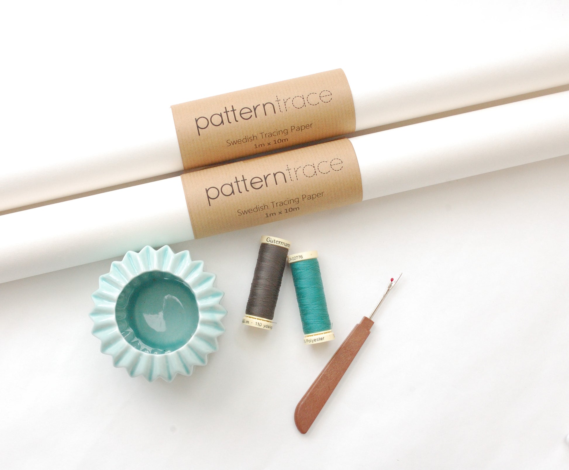 two rolls of Patterntrace tracing paper, a seam ripper and two spools of thread, one teal and one gray