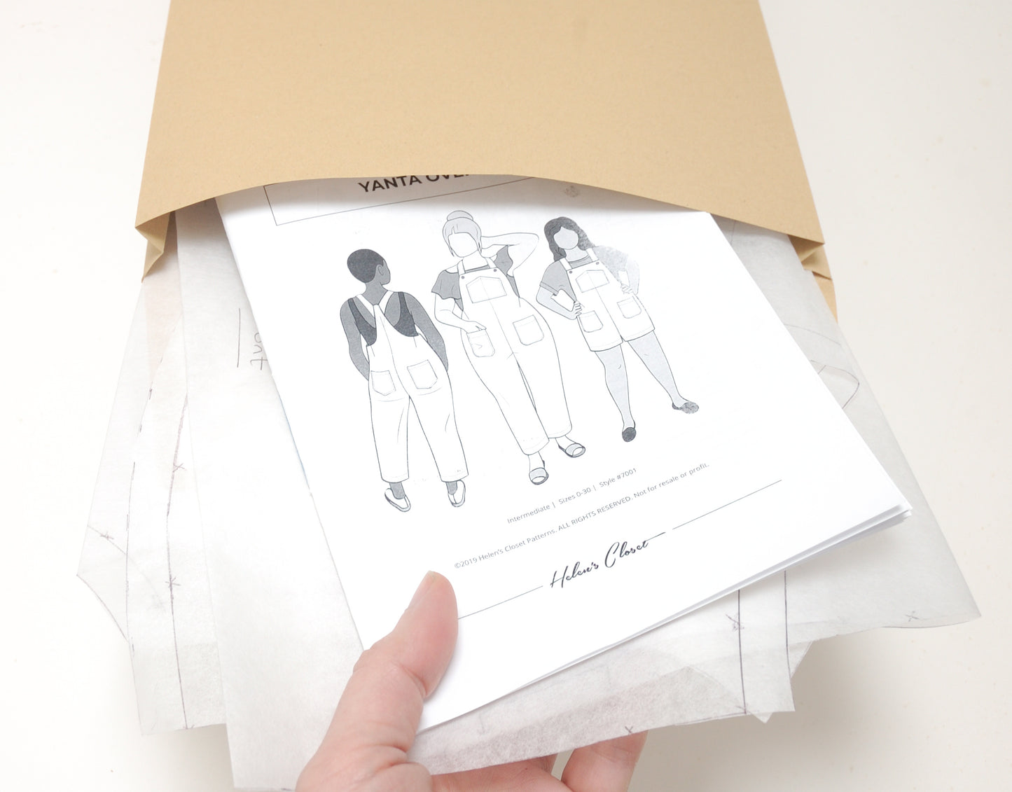 Sewing patterns being put inside a brown paper bag colored sewing envelope