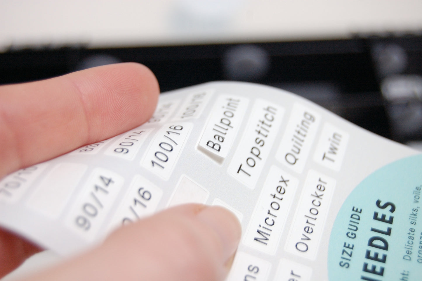 A white paper with rectangle stickers that have sewing needle terms on them
