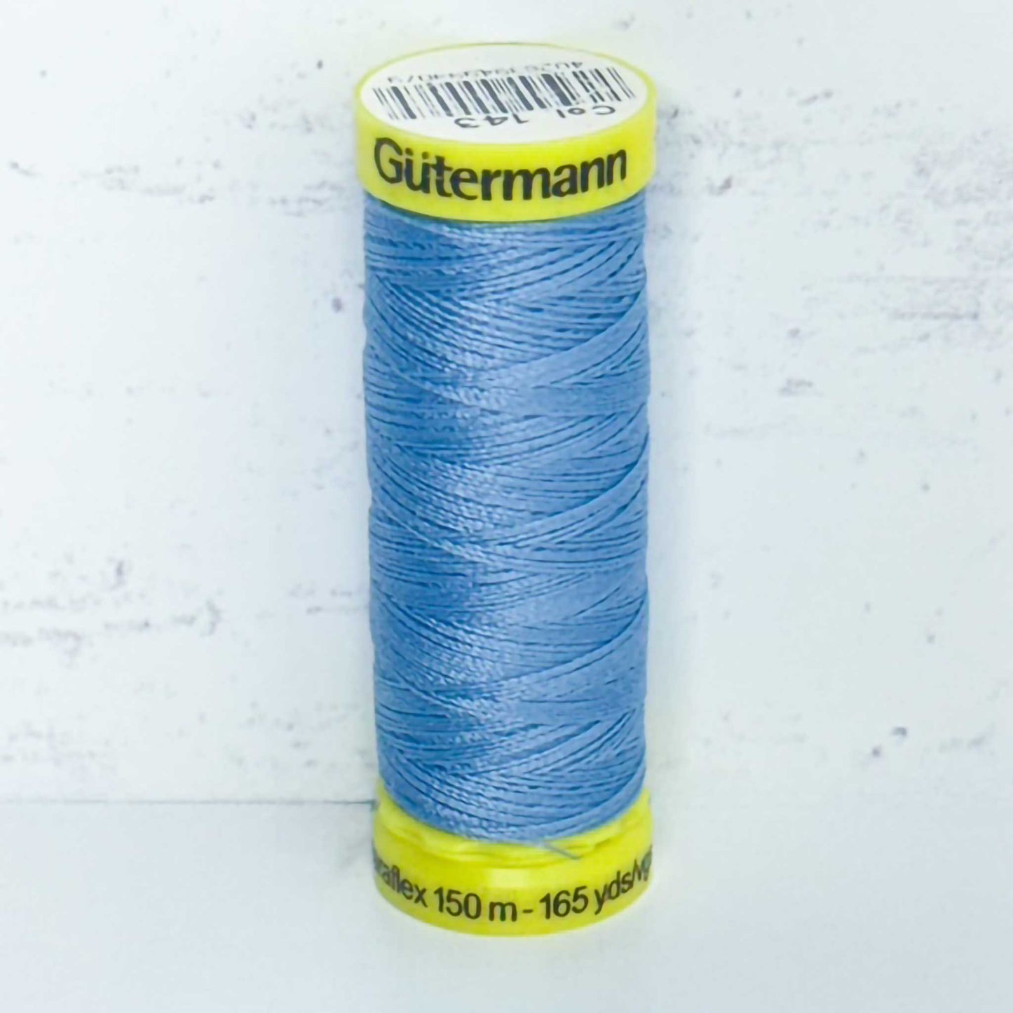 Spool of blue Gutermann thread on a light gray background