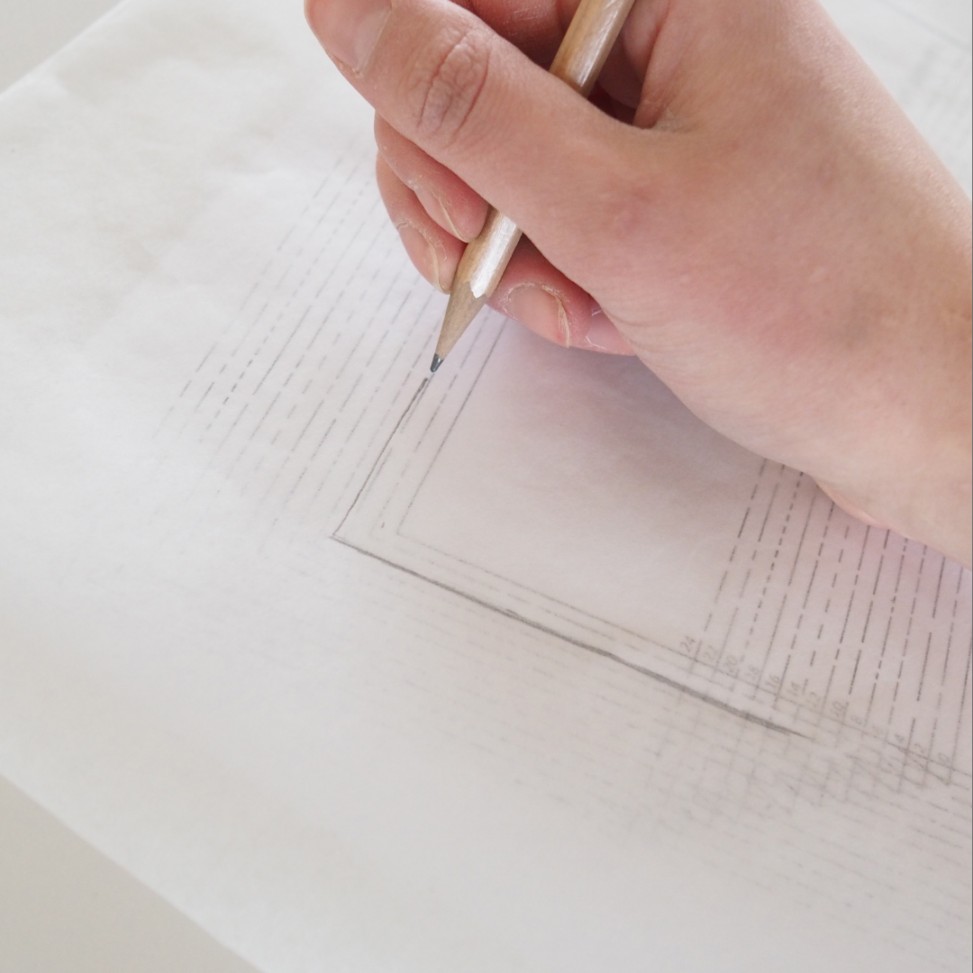 patterntrace paper over a pattern with a hand tracing the pattern to demonstrate the transparency of the paper