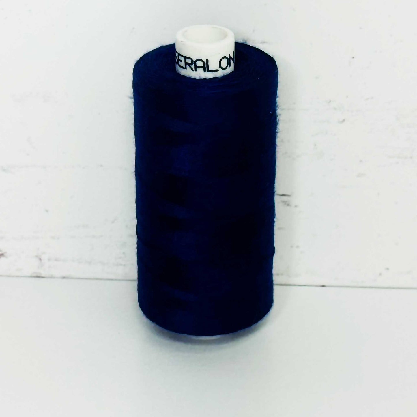 Spool of dark blue thread on a white background