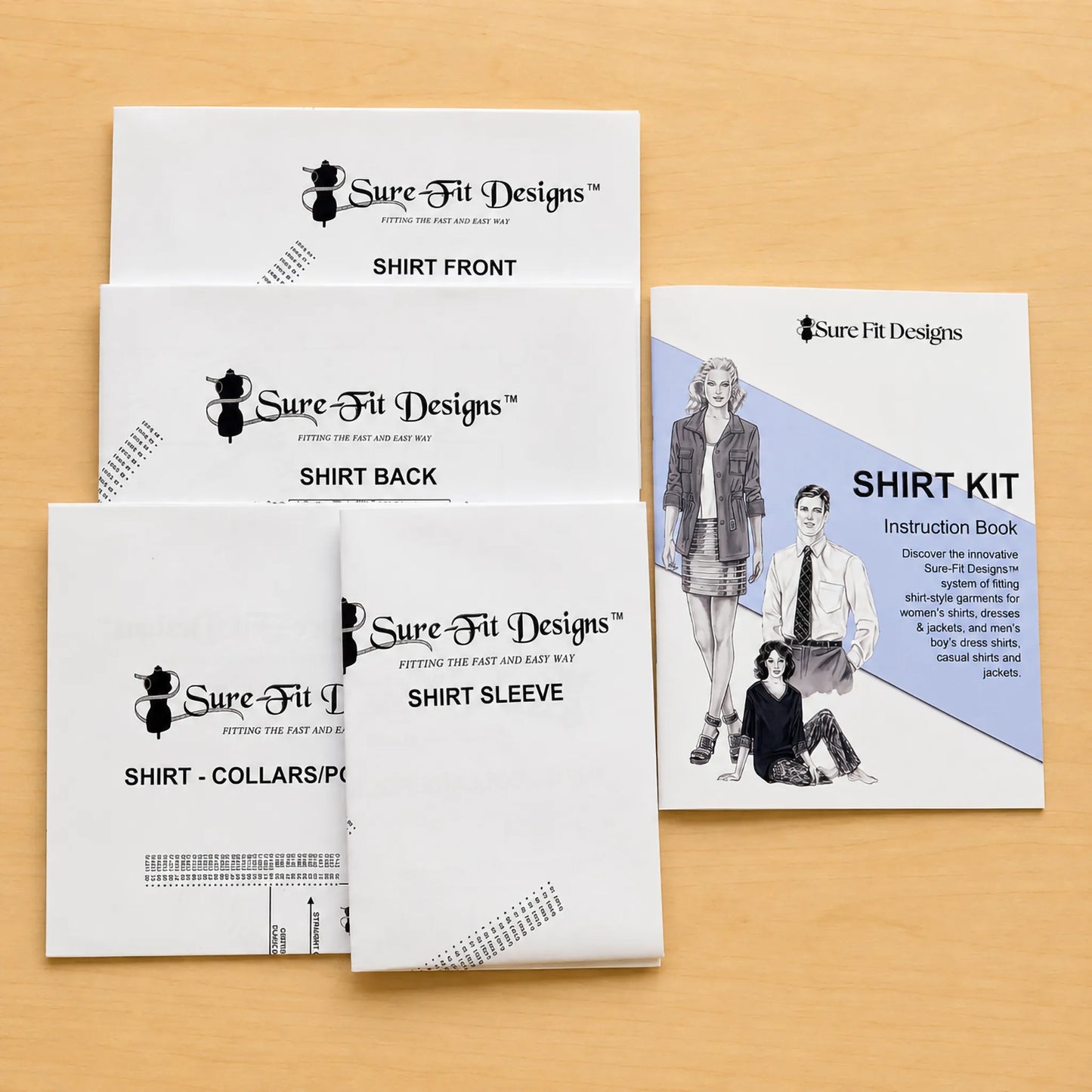A Sure Fit Designs shirt kit instruction book and matching booklet covers arranged on a light wood surface. The white covers show black text and line drawings, including front, back, and sleeve views, alongside the instruction book with a blue panel and illustrated model.