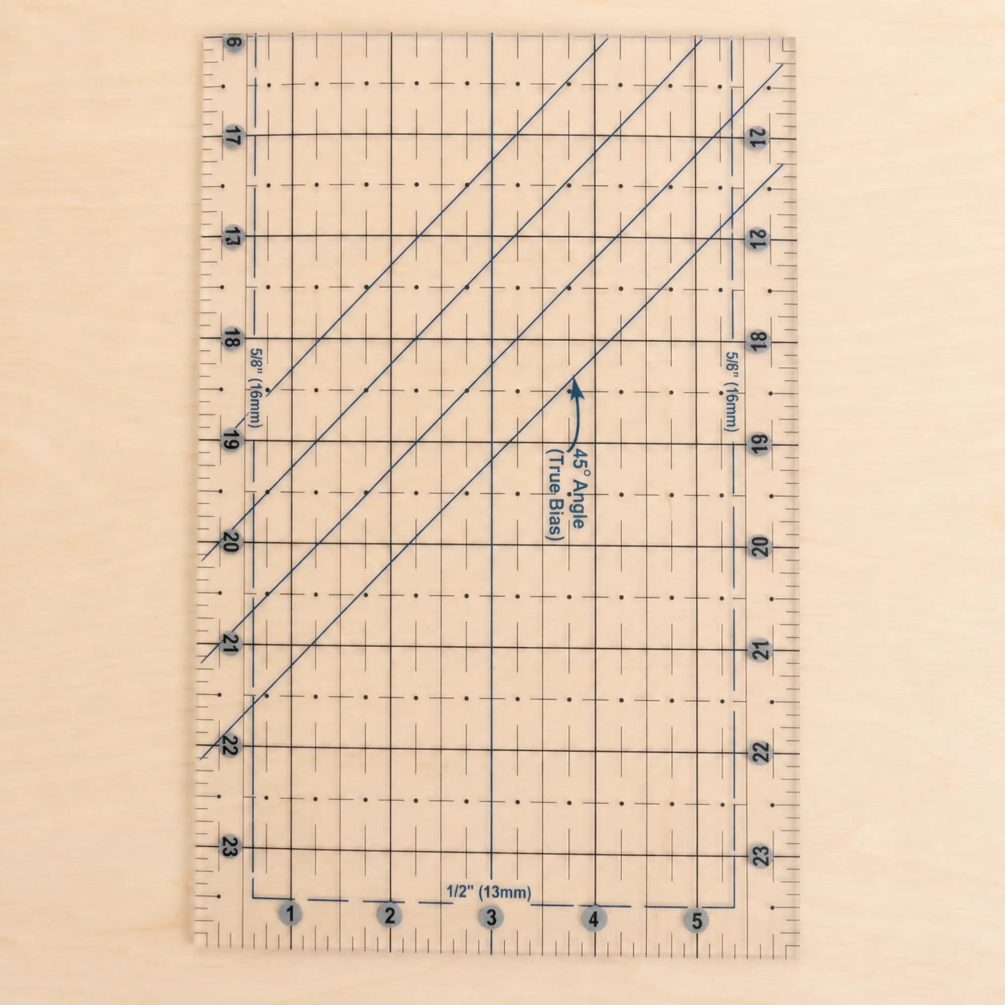 A clear acrylic quilting ruler with blue grid lines, measurement markings, and diagonal conversion guides, shown on a light wood background.