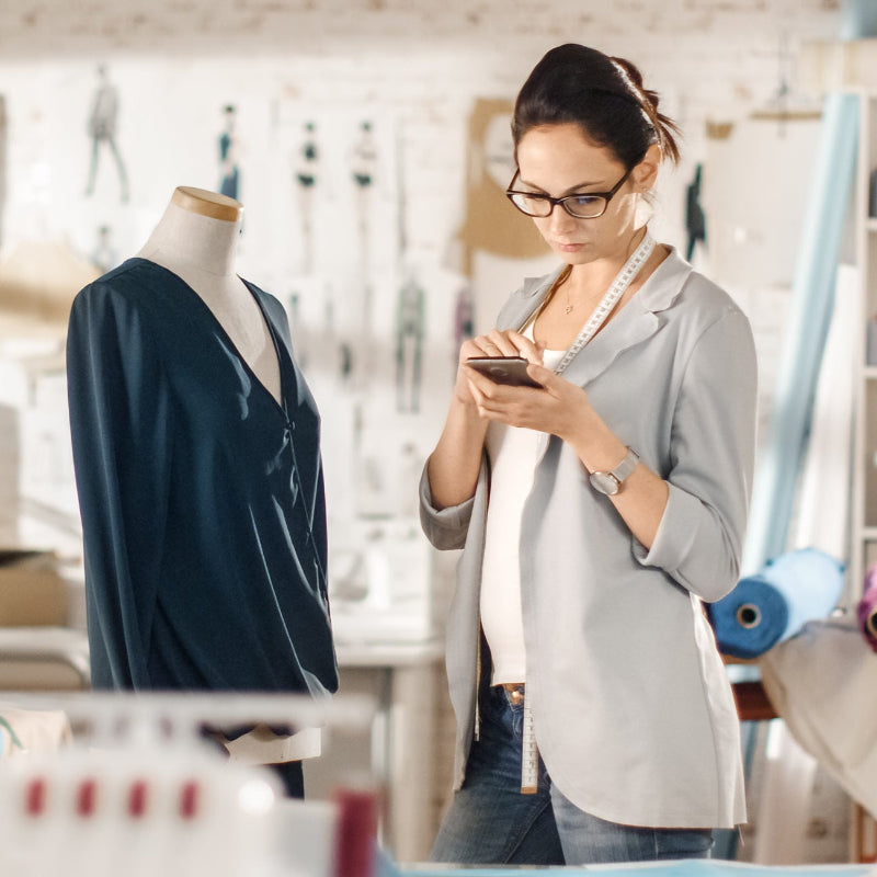Photograph of a beautiful fashion designer studying the making of a garment