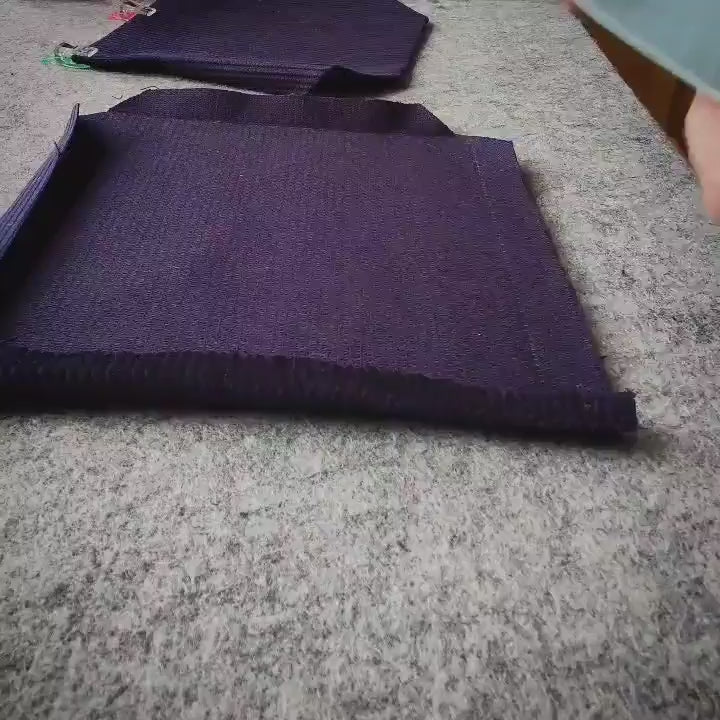 a square of purple fabric on a gray wool mat