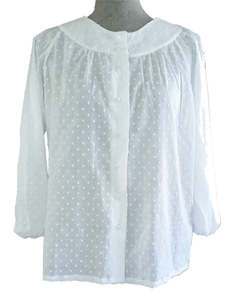 A long sleeved white blouse on a mannequin that buttons up the front