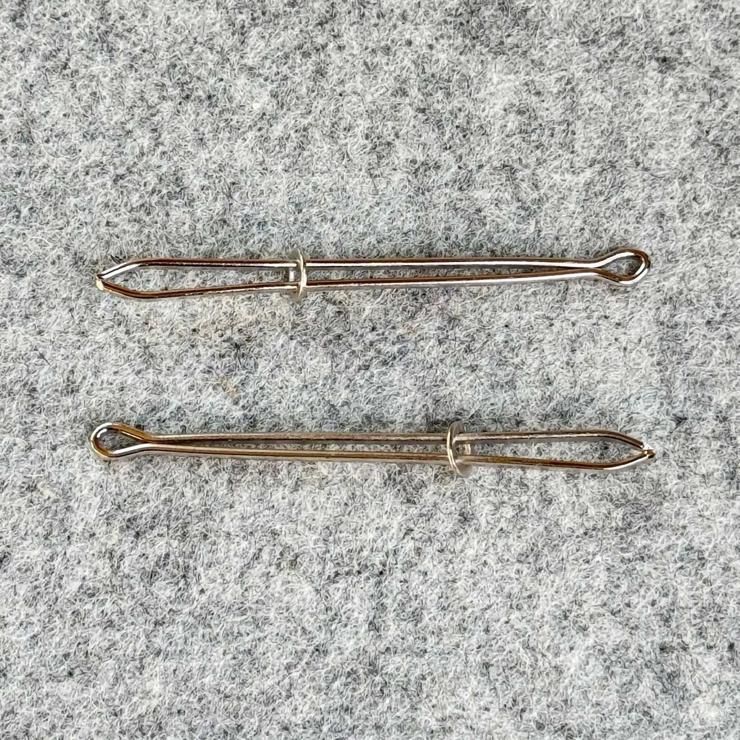 Two bodkins on a textured gray surface