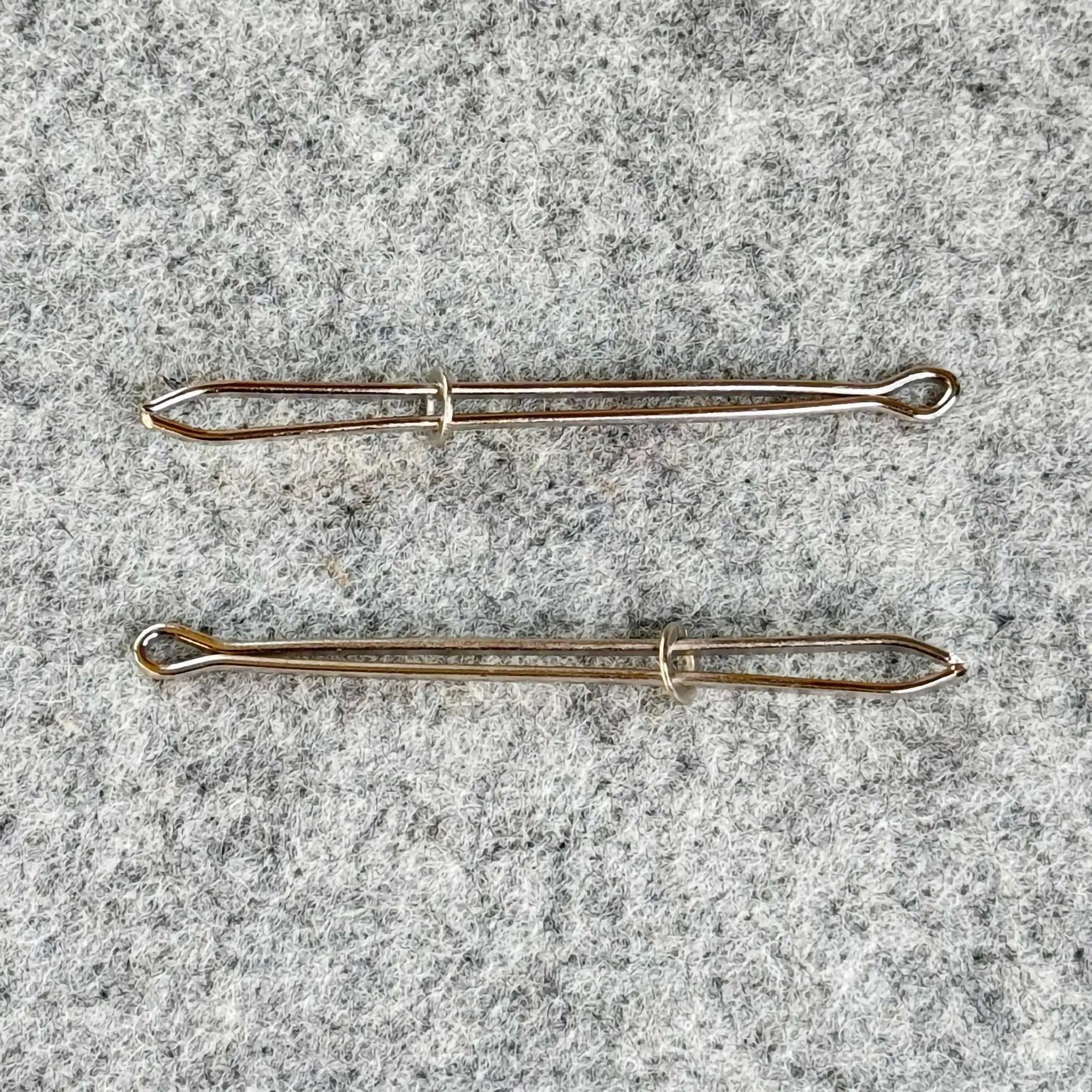 Two bodkins on a textured gray surface