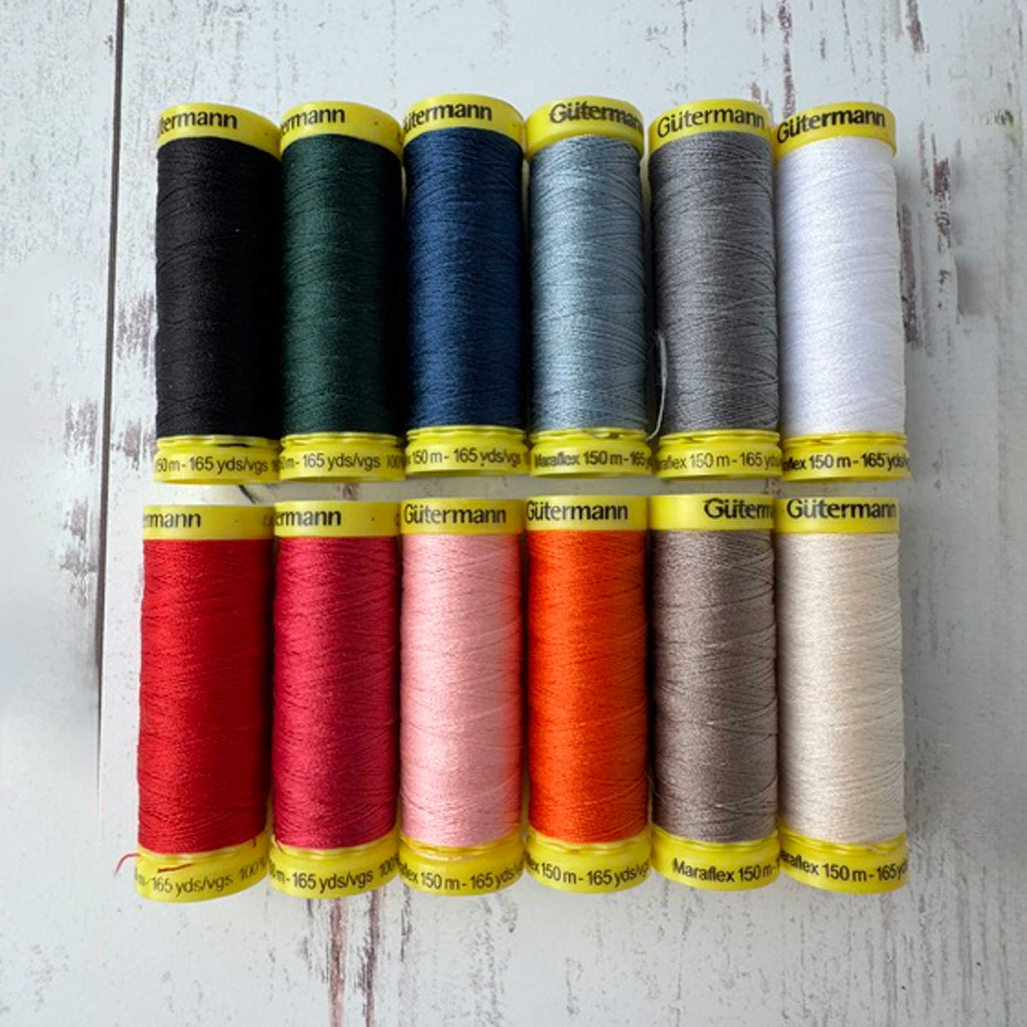 Set of Gutermann thread spools in various colors on a wooden surface