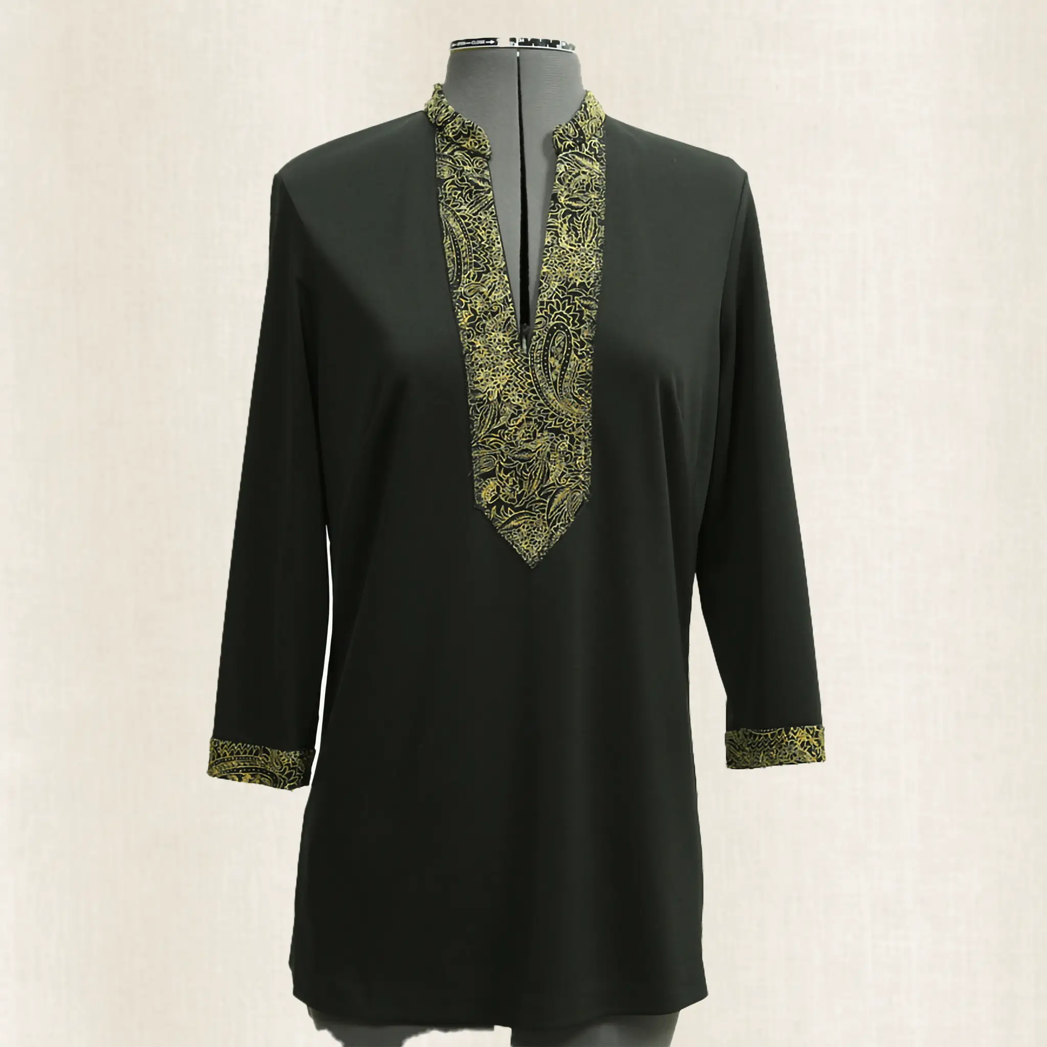 Black dress with green embroidery on a mannequin against a white background