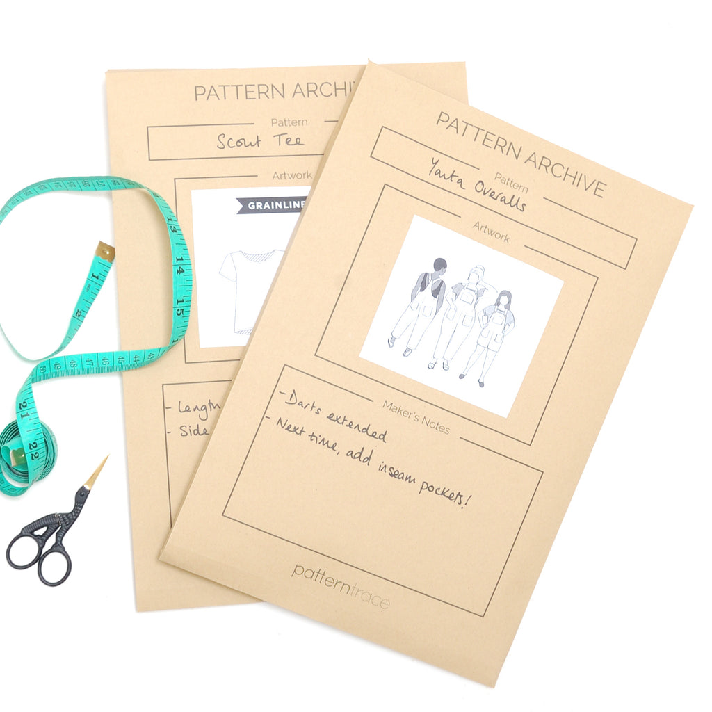 two large paper bag colored Pattern Archive envelopes from Patterntrace that has a teal measuring tape and bird shaped scissors on the left 