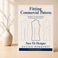 A Fitting Commercial Patterns course displayed on a light maple table with a small vase of branches.