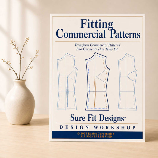 A Fitting Commercial Patterns course displayed on a light maple table with a small vase of branches.