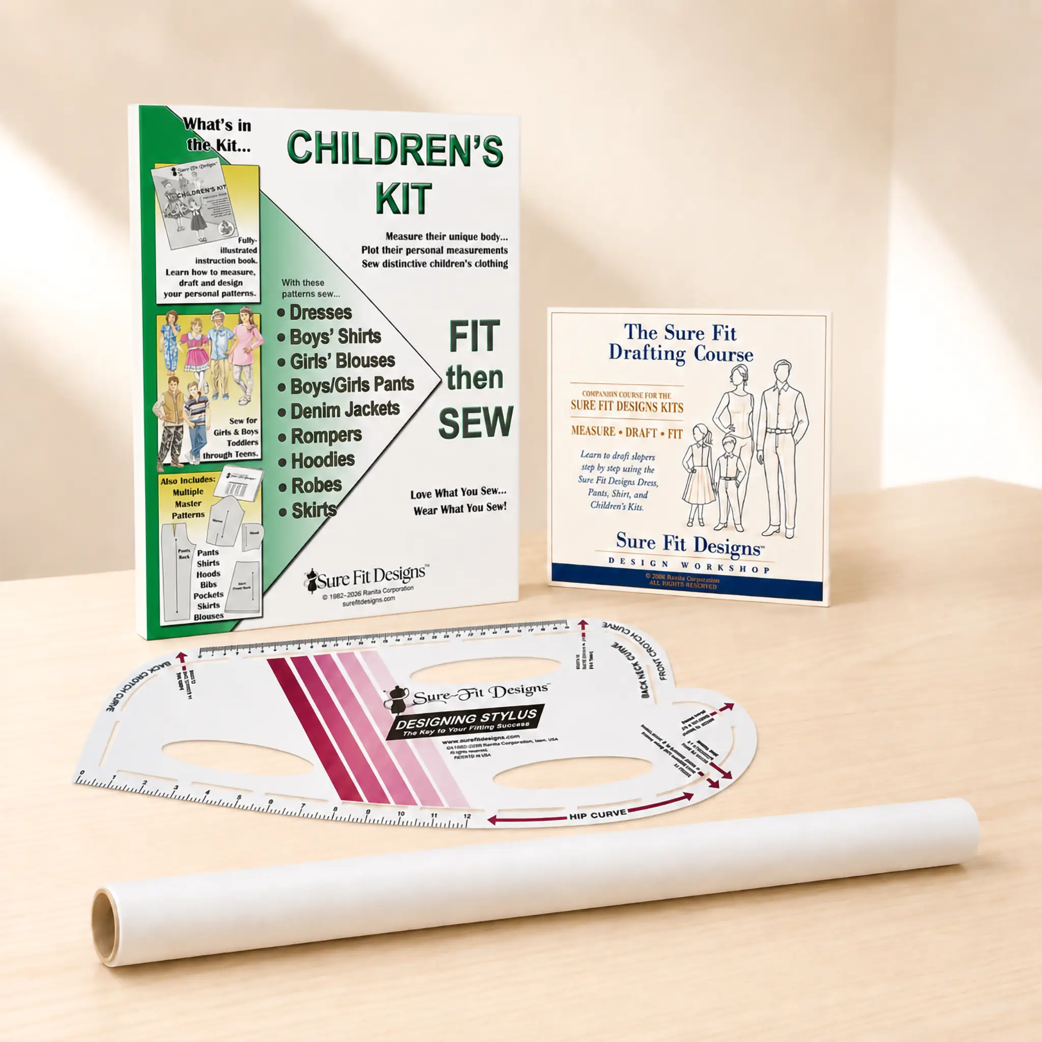 A children's sewing kit set displayed on a light wood surface, including a printed 'Children's Kit' booklet, a drafting course card, a curved ruler, and a spool of thread.