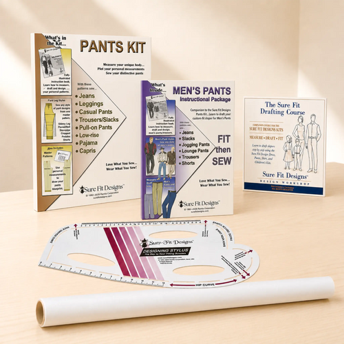 Sure Fit Designs pants fitting kit displayed on a light wood surface with a beige background. The kit includes instruction booklets, a pattern transfer sheet, a curved measuring template, and a rolled transfer sheet.