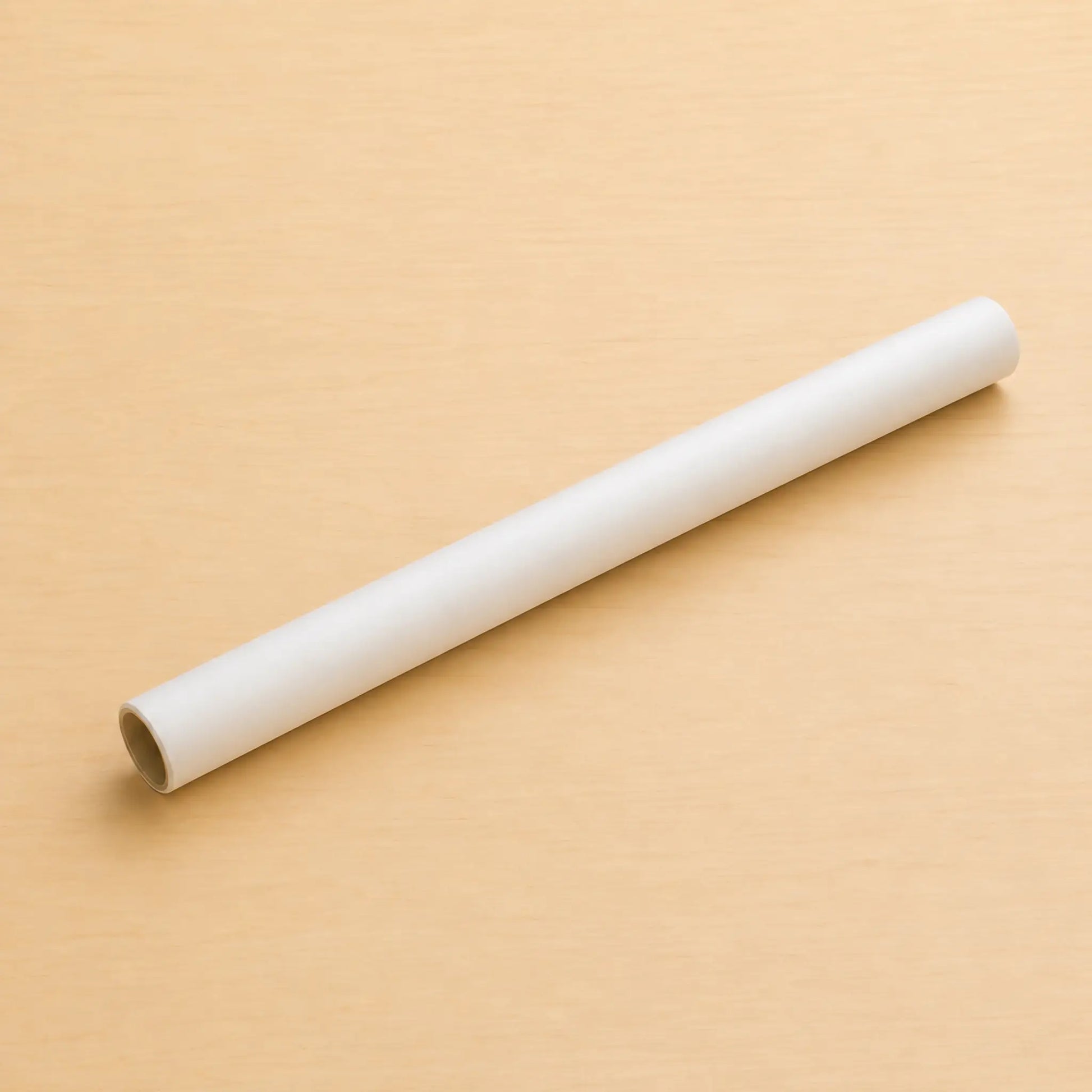 A roll of white Hahnemühle transparent tracing paper lying diagonally on a light maple table
