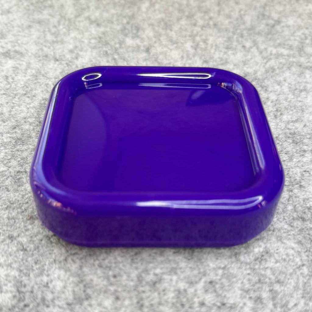 Purple plastic container lid on a gray surface