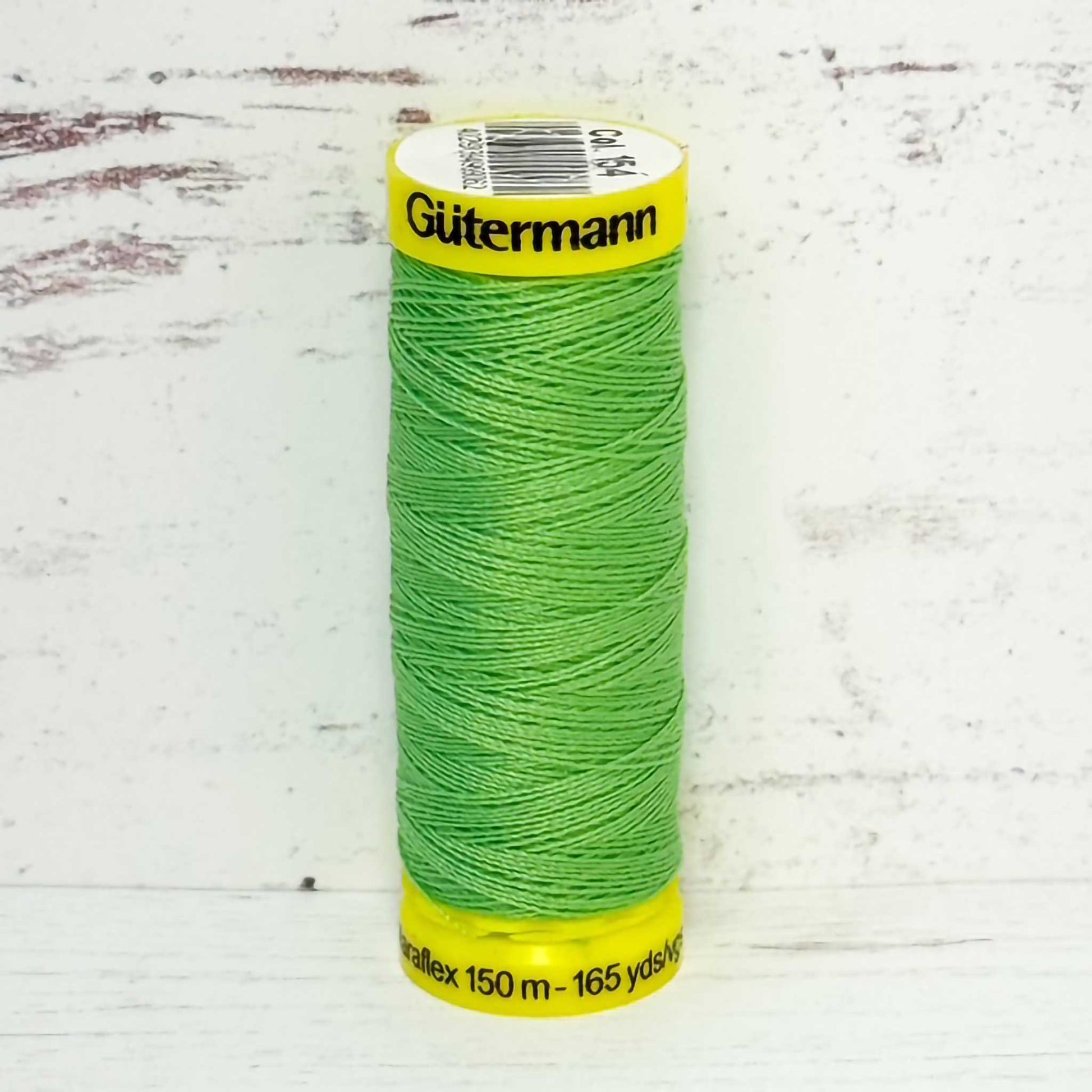 Green spool of light green Gutermann thread on a light gray background