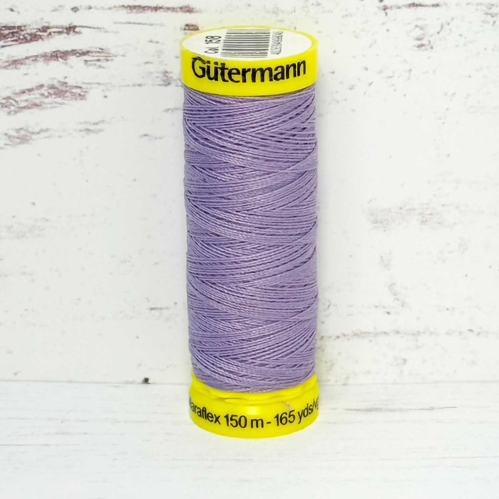 Spool of lavender Gutermann thread on a light wooden surface