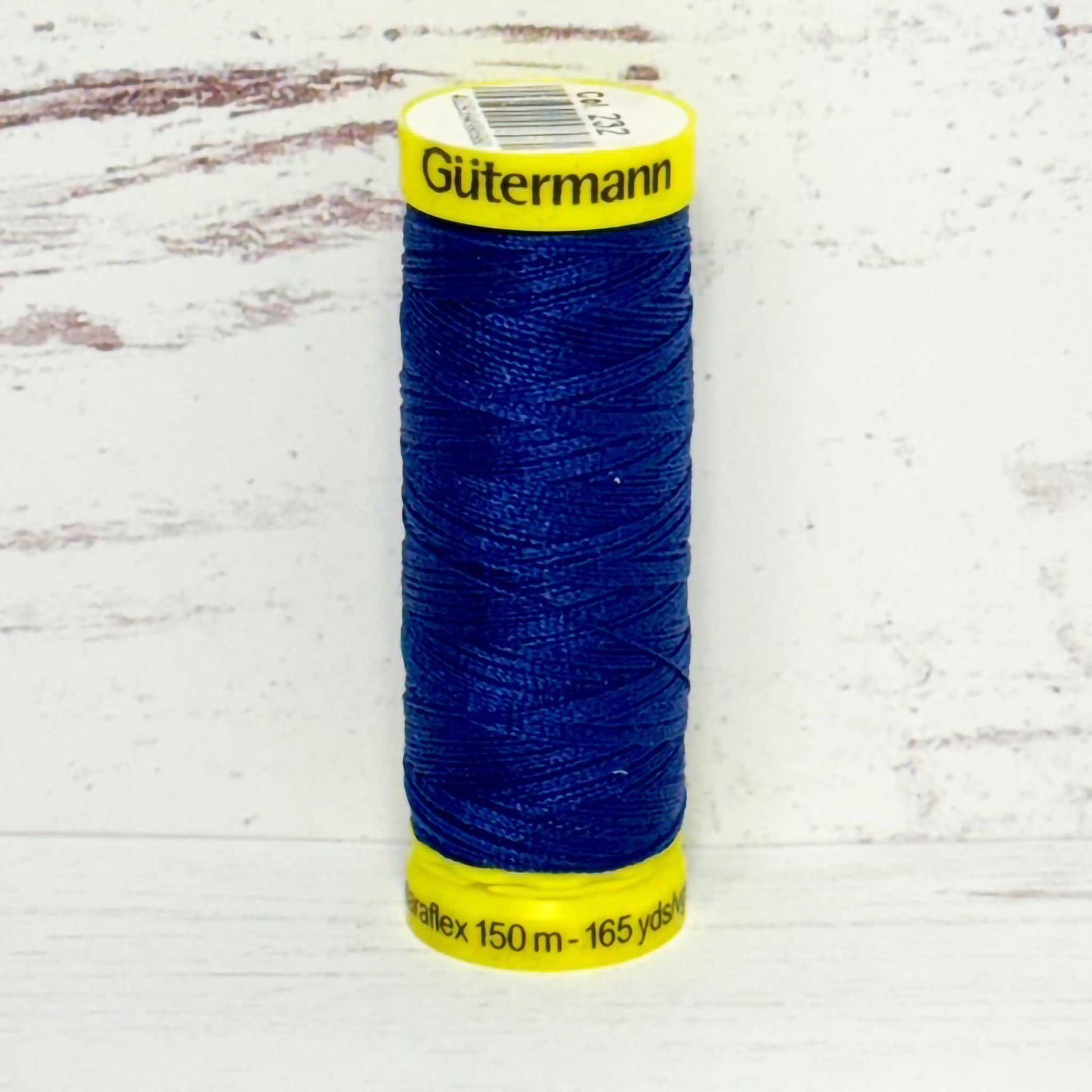 Spool of blue thread with yellow label on a light gray background