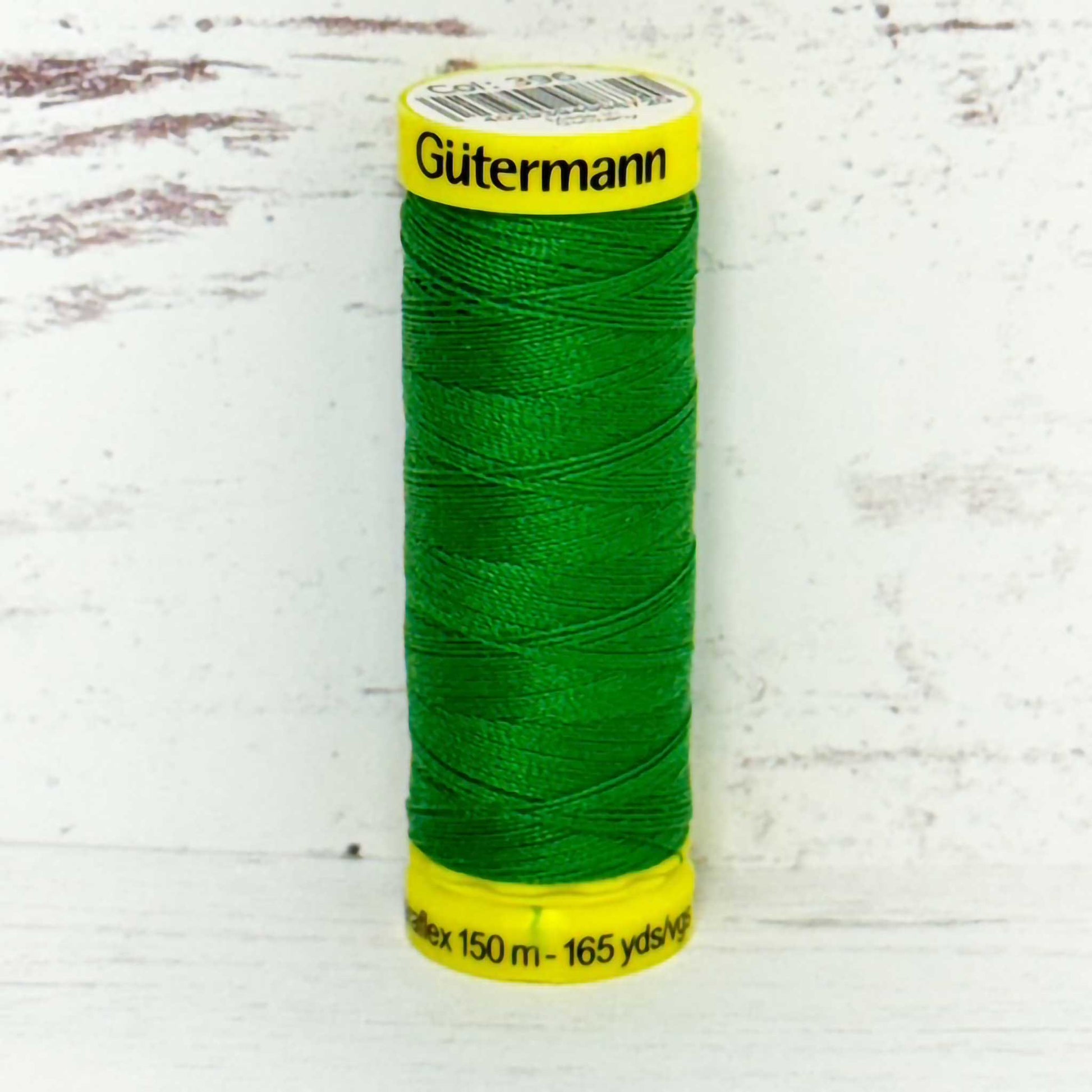Green spool of Gutermann thread on a white background