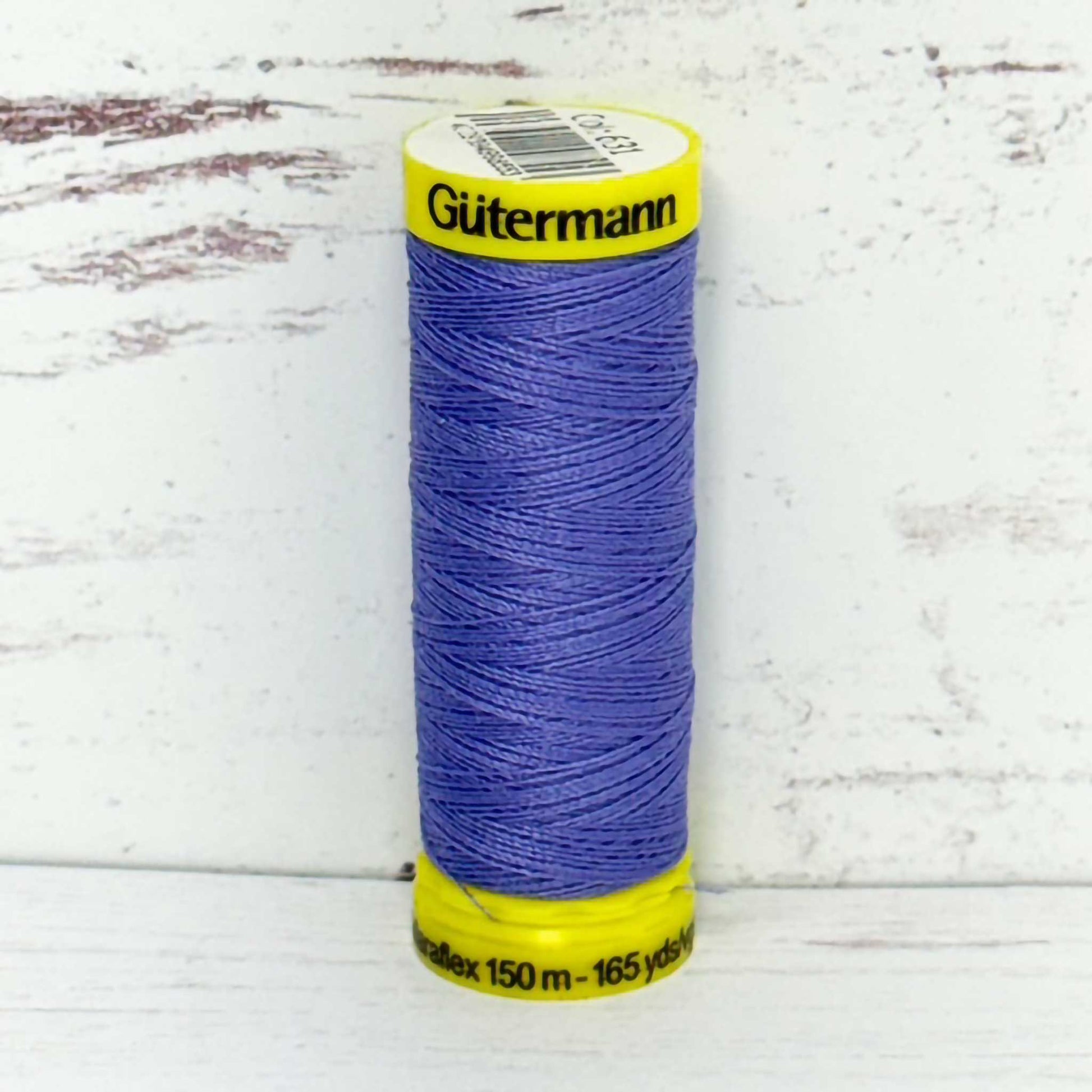 Spool of lilac thread with yellow label on a white wooden surface