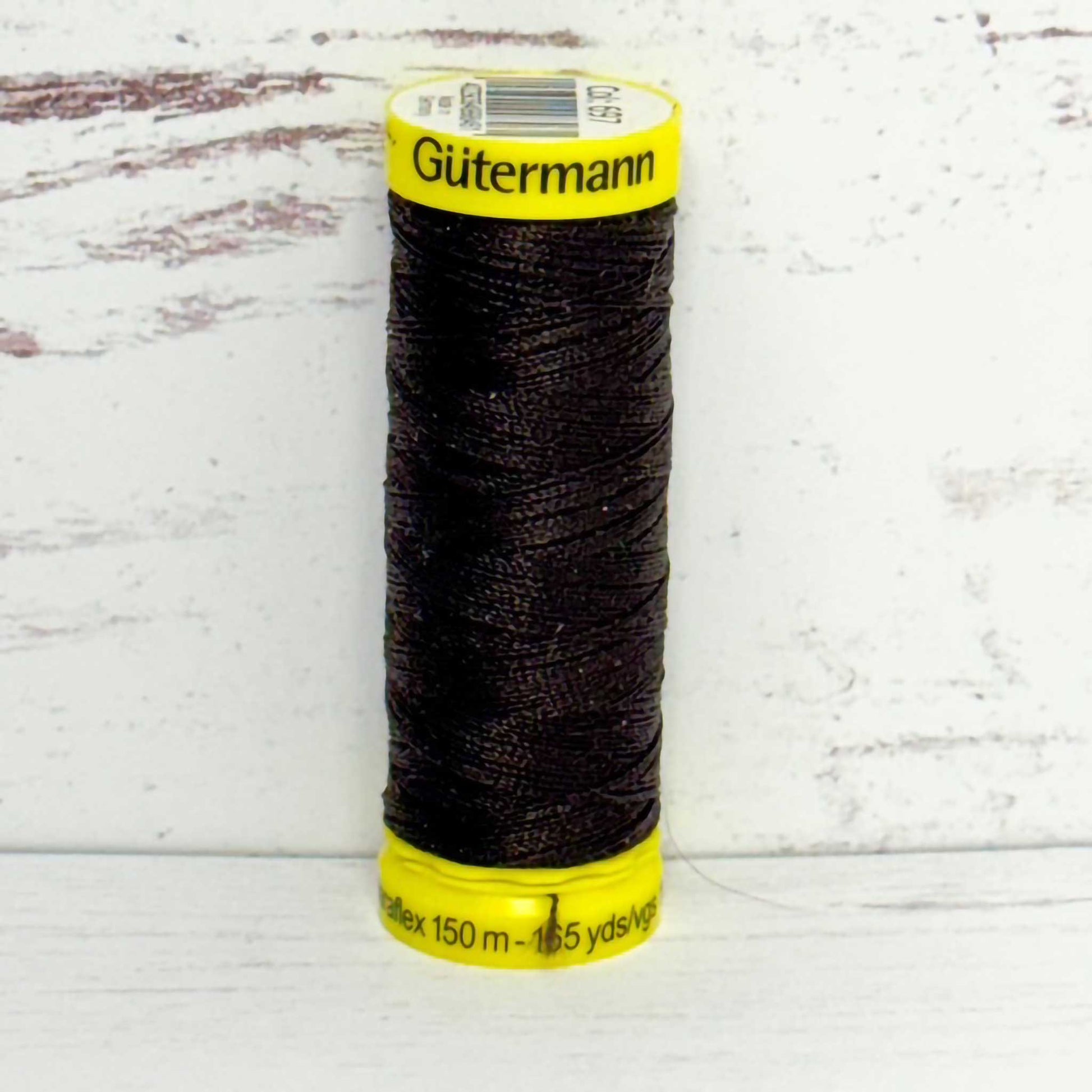 Spool of brown thread with yellow label on a light wooden background