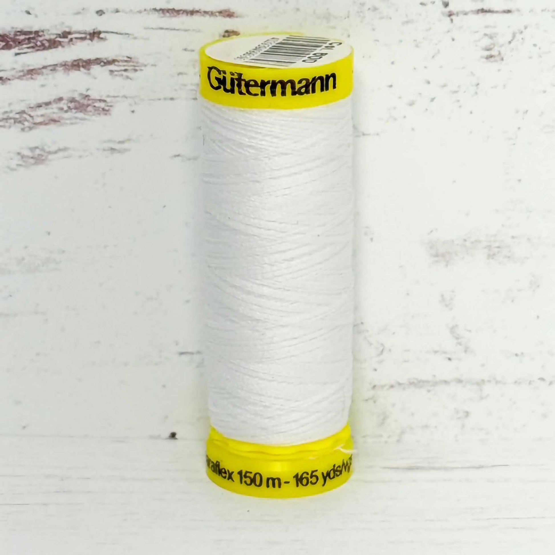 Spool of white  Gutermann thread on a textured white background
