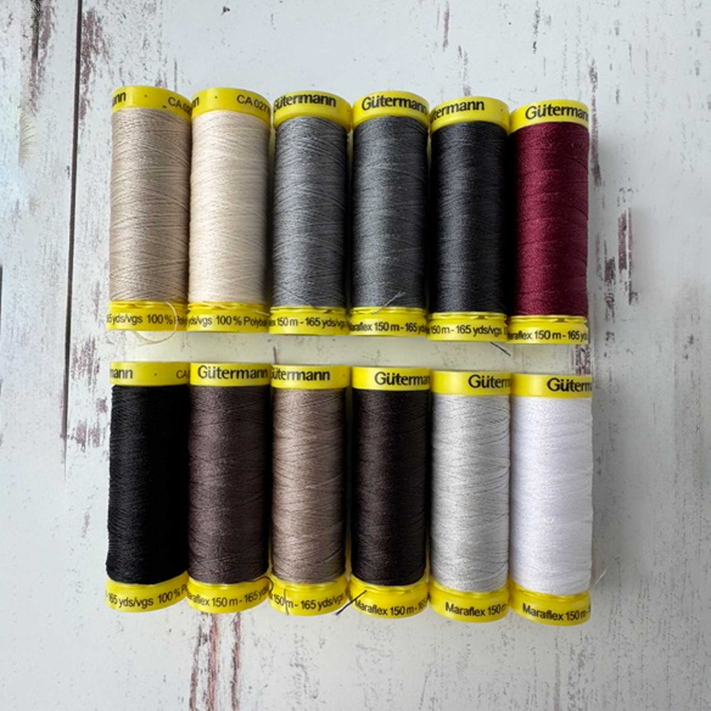 Set of Gutermann thread spools in various colors on a wooden surface