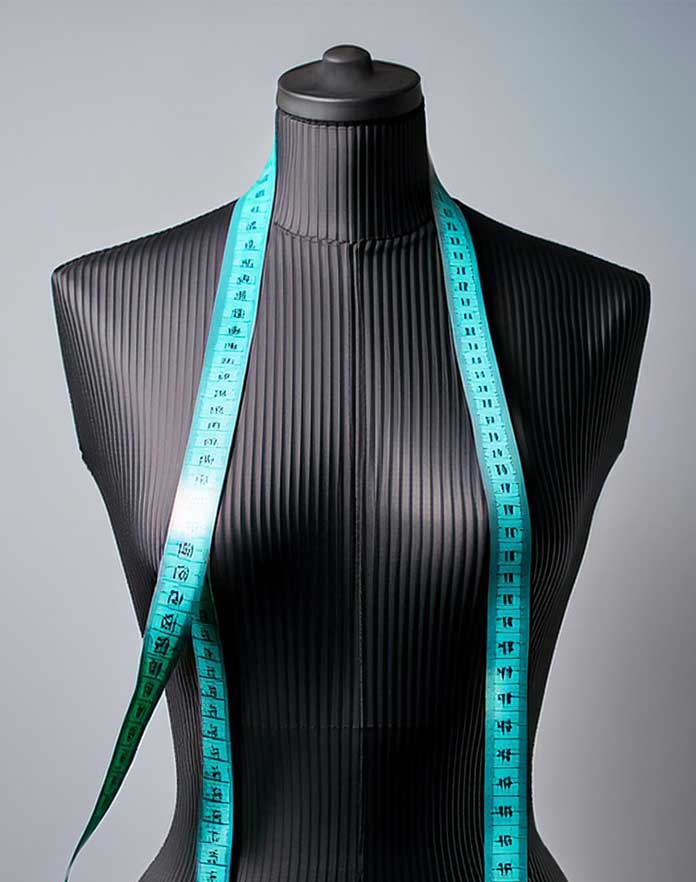 A black female mannequin torso with a teal tape measure draped around the neck