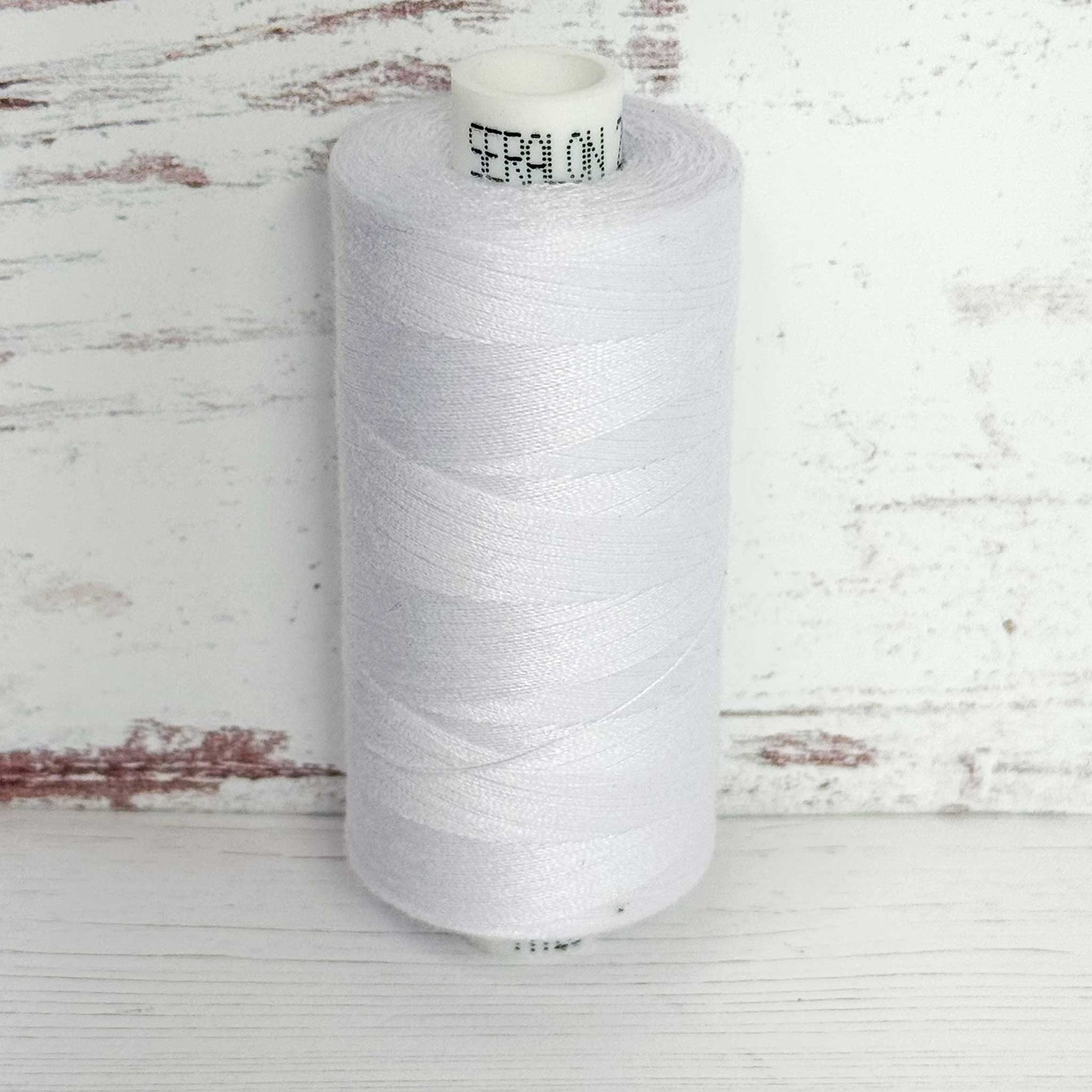 Spool of white thread with 'Seralon' branding on a wooden surface