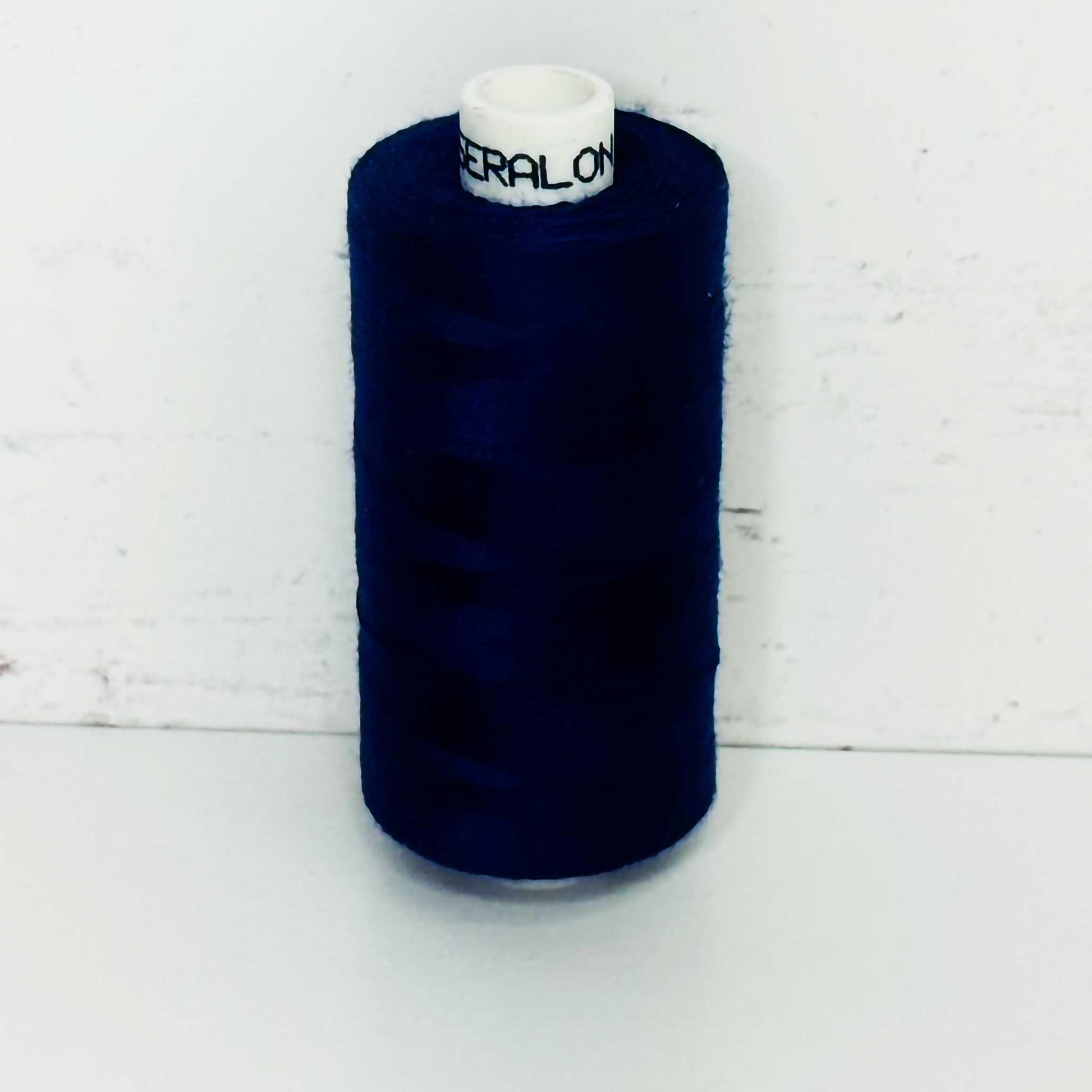 Spool of dark blue thread on a white background