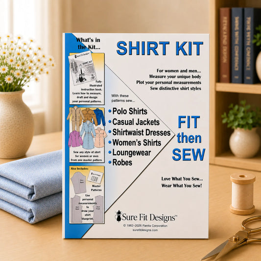 A 'Shirt Kit' sewing pattern box by Sure Fit Designs stands on a wooden table, surrounded by a folded blue shirt, a spool of thread, scissors, and books in the background.