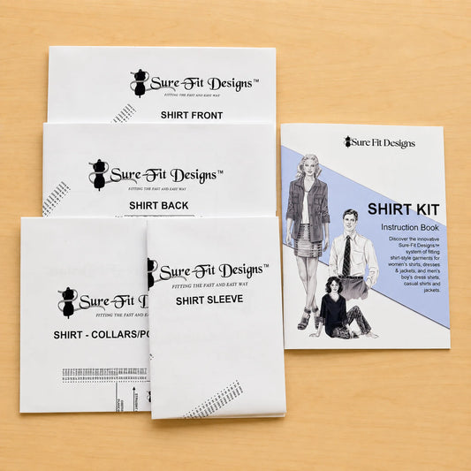 A Sure Fit Designs shirt kit instruction book and matching booklet covers arranged on a light wood surface. The white covers show black text and line drawings, including front, back, and sleeve views, alongside the instruction book with a blue panel and illustrated model.