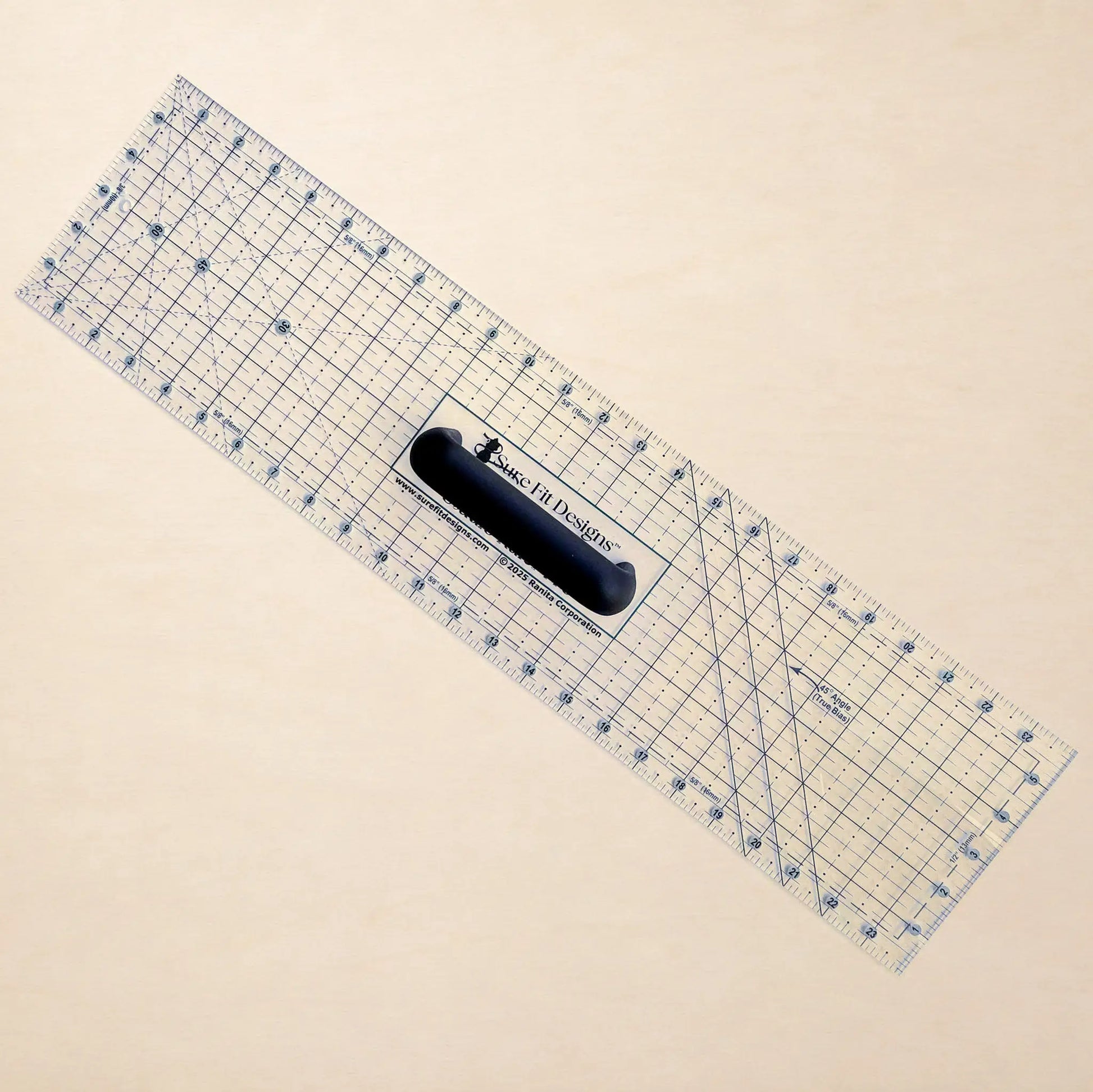 A clear acrylic rotary cutter with blue grid lines and a black handle, shown diagonally on a light beige background. The brand 'Made In Design' is printed on the handle.