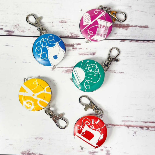 five retractable tape measure/key chains for sewing with colorful sewing themes 