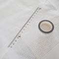 a spool of washi tape viewed from the top and a strip of tape diagonally above it.  The tape is white with black ink measuring centimeters