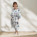 Woman wearing a floral dress standing against a plain background