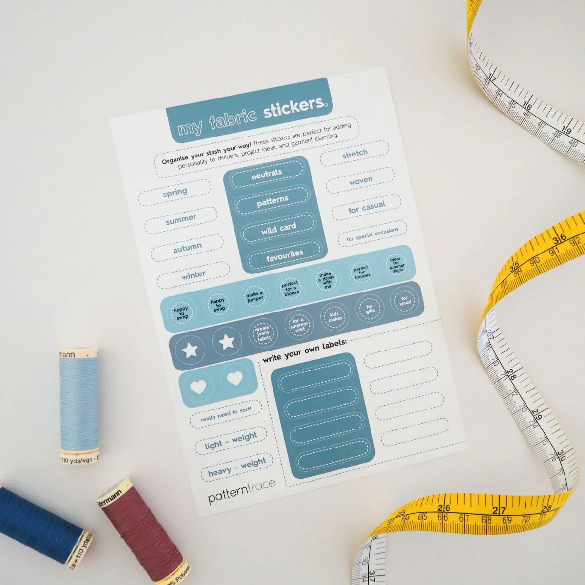 a page of stickers that are shades of blue on a white background that describe the  seasons and occasions to wear clothing.  There is a yellow and white tape measure on the right and blue and red spools of thread on the left