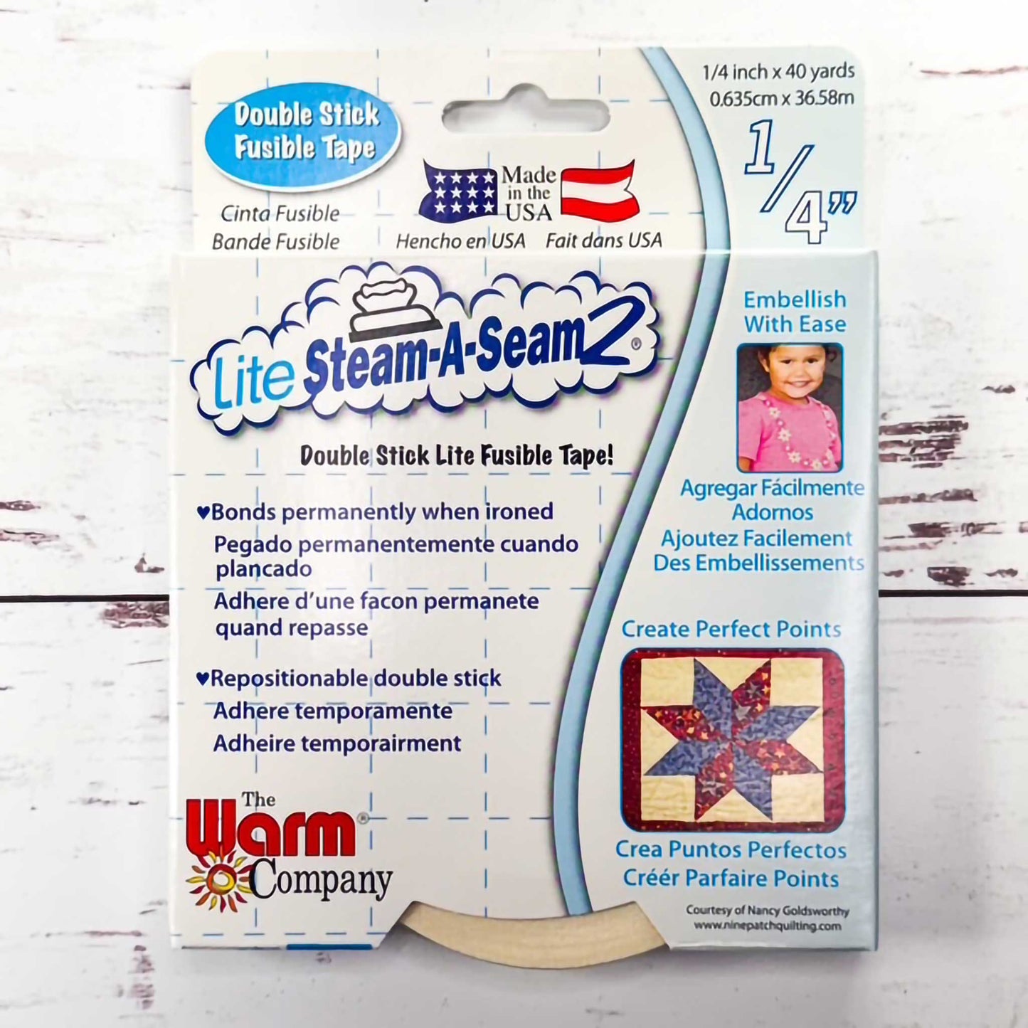 Package of Lite Steam-A-Seam 2 double stick fusible tape with a wooden ruler on a white background