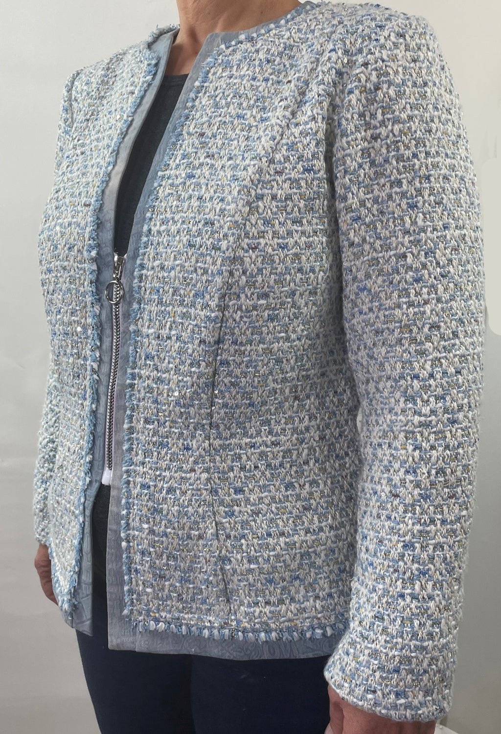 A close up of a mid zipper on a jacket made of blue brocade fabric seen from a 45 degree angle of the front