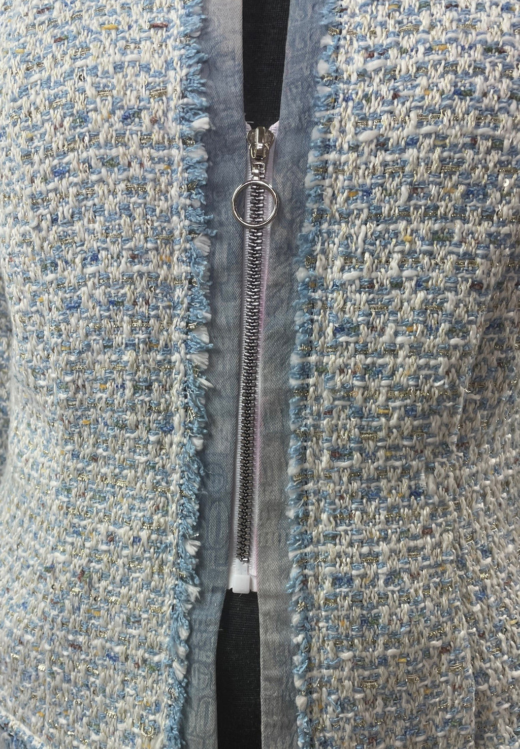 A close up of a mid zipper on a jacket made of blue brocade fabric