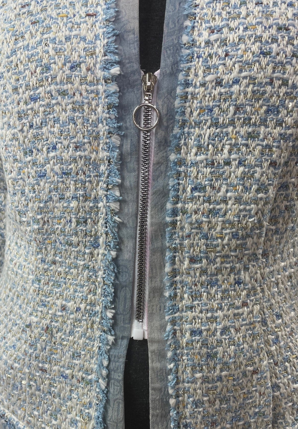 A close up of a mid zipper on a jacket made of blue brocade fabric