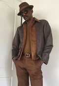 A digital sewing pattern for a shacket. A stylish black model is wearing a brown hat, sunglasses and a stylish jacket and pants.  