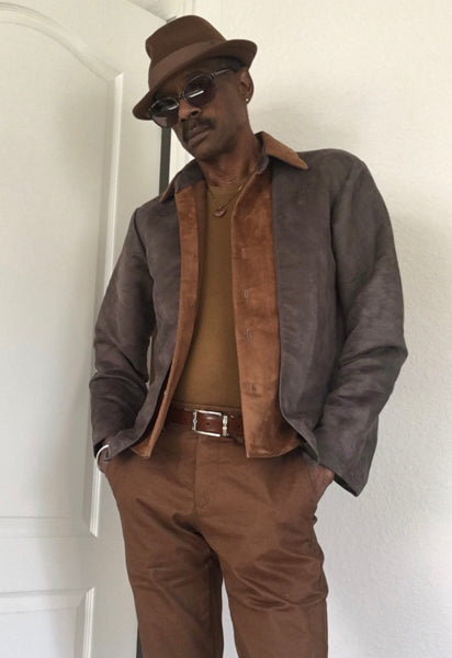A digital sewing pattern for a shacket. A stylish black model is wearing a brown hat, sunglasses and a stylish jacket and pants.  